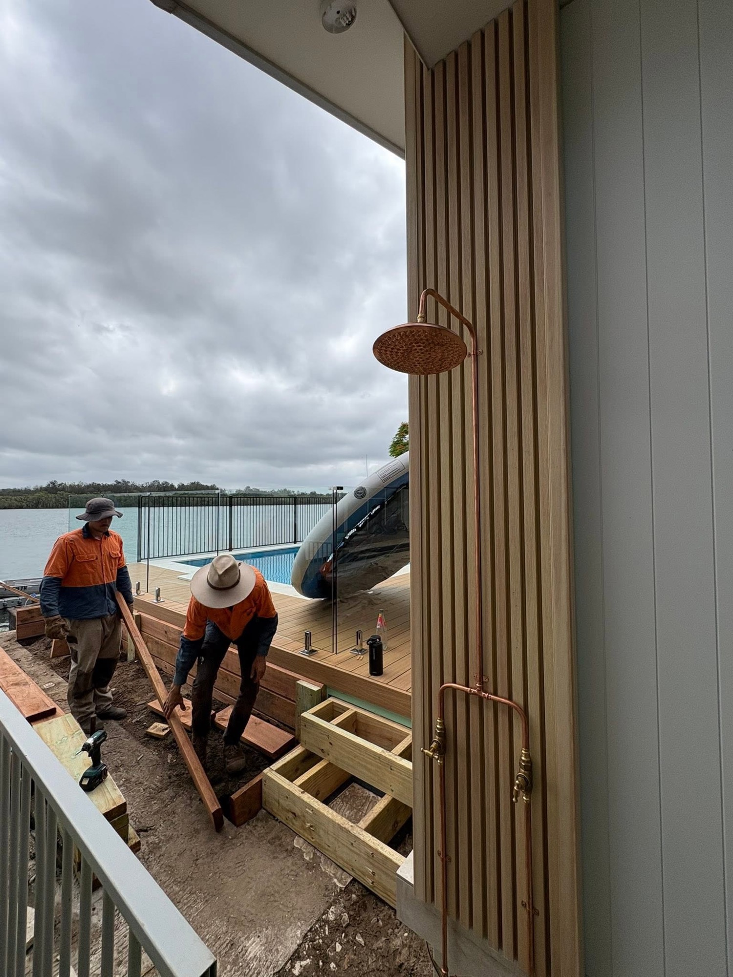 Two Temple Constructions tradesmen building a timber deck beside the water