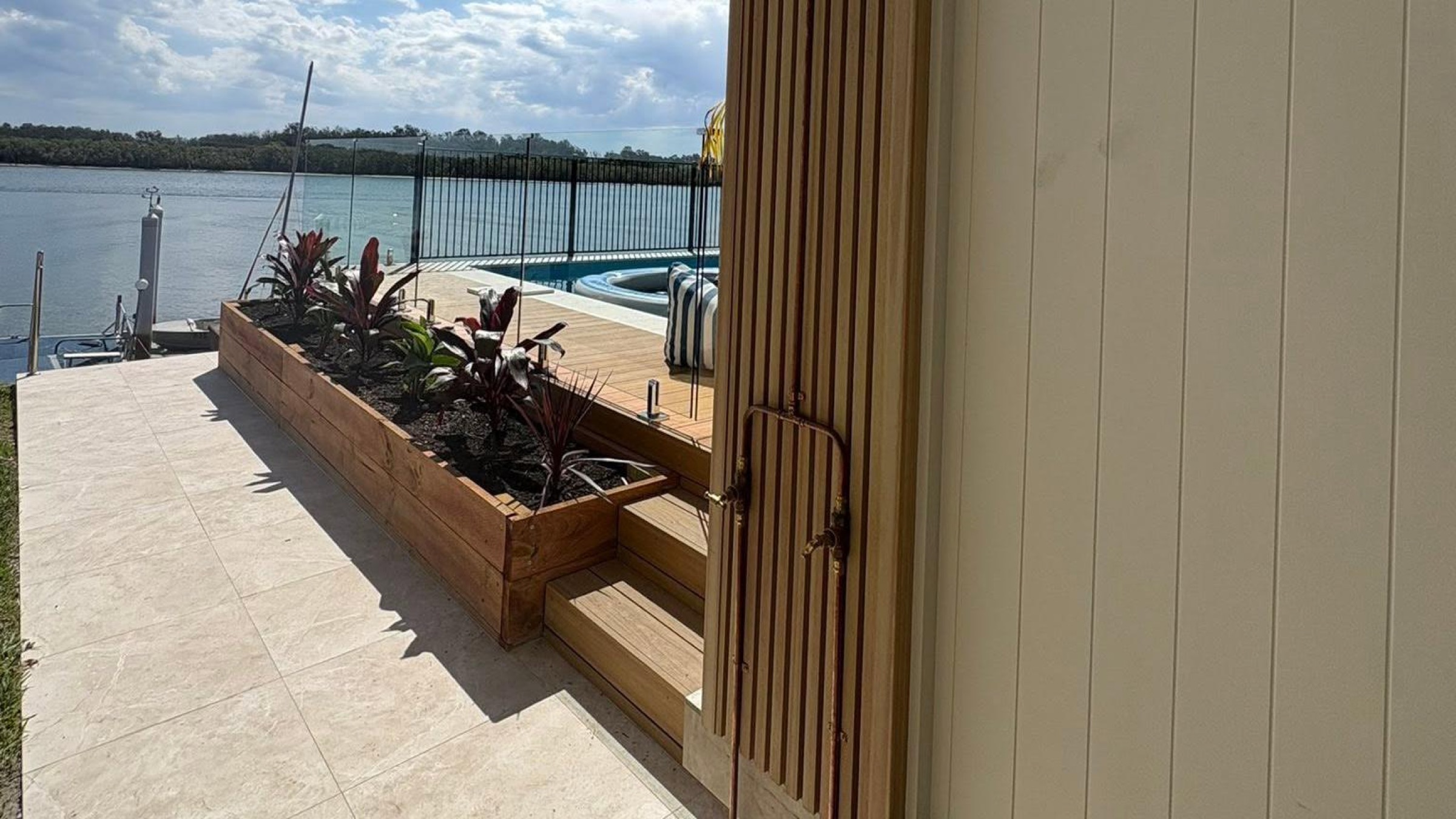 Timber deck steps and garden planters beside a pool
