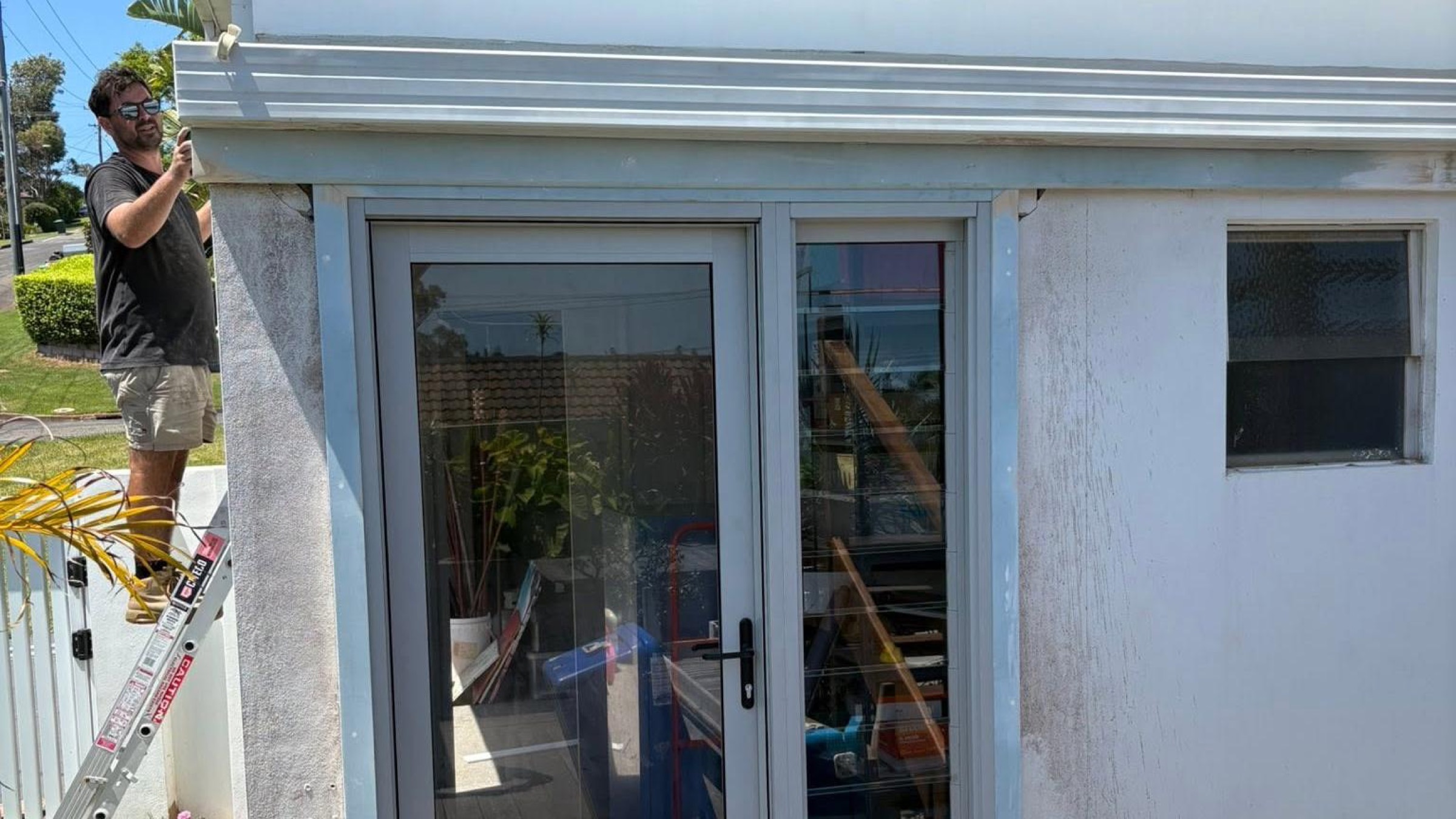 A tradesman working on the exterior of a two-storey home