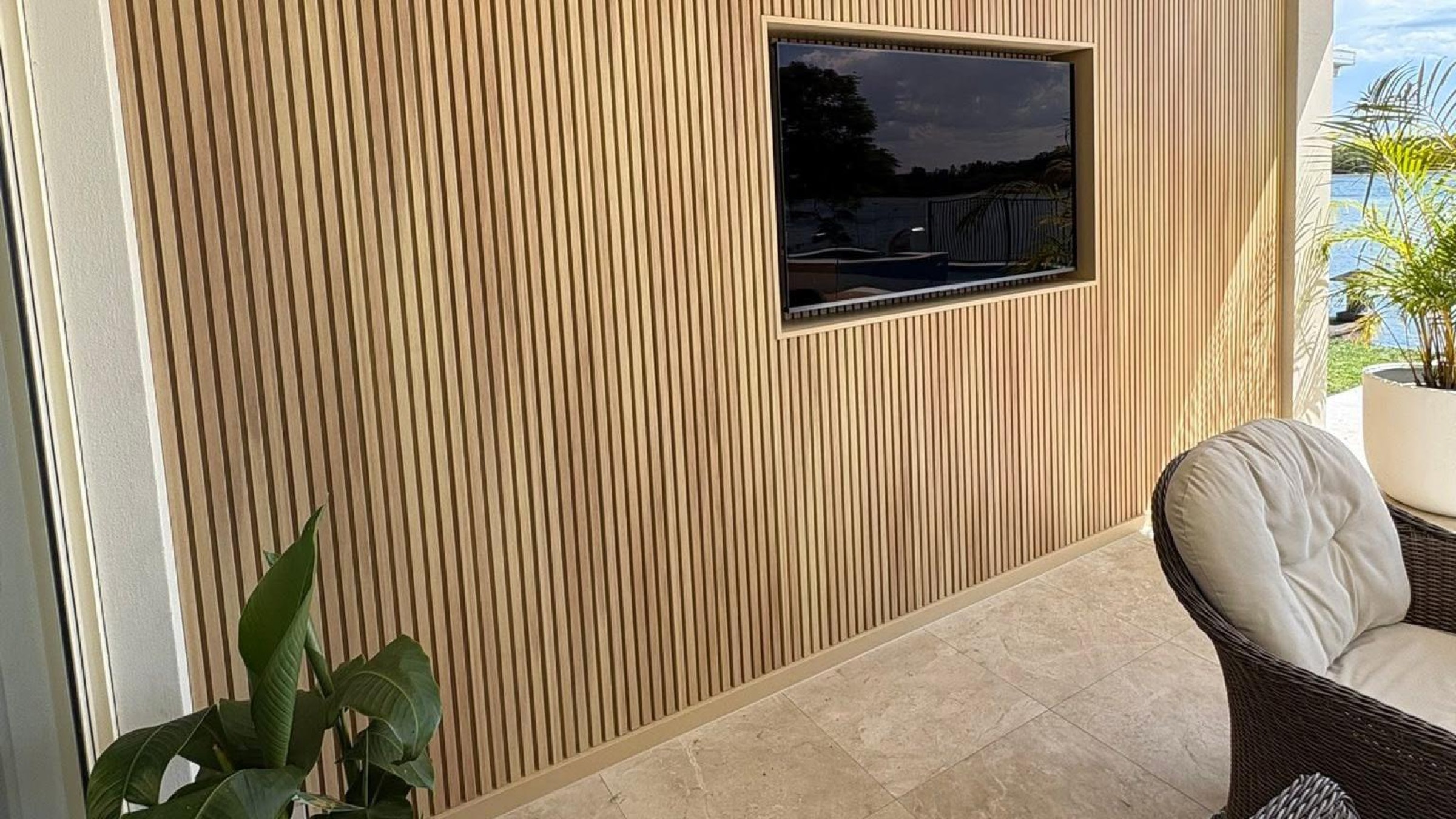 A timber slat feature wall with a mounted TV opening onto a deck
