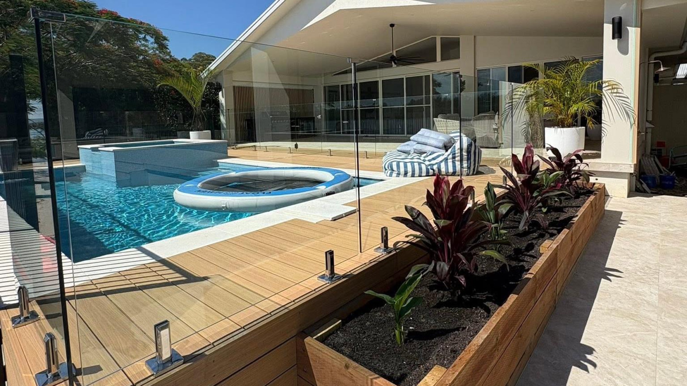 A timber deck and pool with garden planters overlooking the water